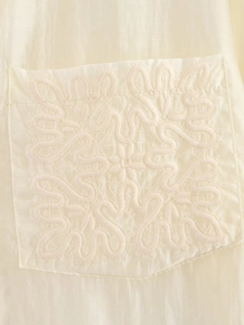 Detailed view of intricate tonal floral embroidery on a beige silk texture pocket shirt