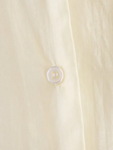 Macro detail of cream shirt showing vertical texture and translucent button