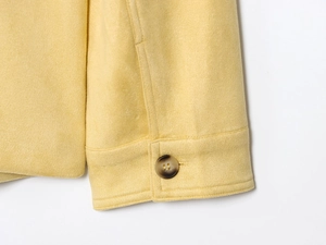 Detail of yellow wool fabric texture with dark marble button on sleeve cuff