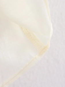 Detailed close-up of high-quality stitching and hem on a white long-sleeved shirt fabric