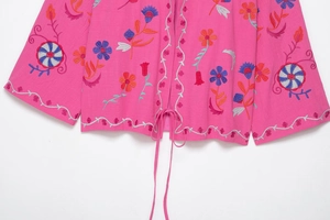Détail de la broderie florale et de l'ourlet à nouer sur cardigan en coton rose