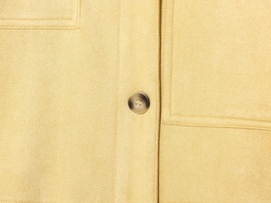 Detail of yellow faux suede jacket featuring tortoiseshell button and premium stitching