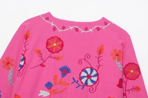 Gros plan sur la broderie florale ethnique et la texture du tissu du cardigan rose