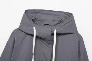 Detail view of the gray hooded jacket collar with white drawstrings and windproof flap