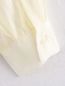 Close-up of cream shirt cuff with glossy fabric texture and neat button detail