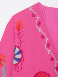 Détails de broderies florales bohèmes et tissu texturé sur un cardigan rose magenta