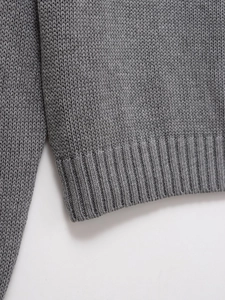 Gros plan d'un pull en tricot gris montrant l'ourlet côtelé et la texture fine