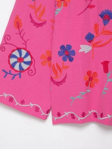 Gros plan détaillé de broderies florales sur la manche d'un cardigan rose vif