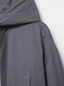 Macro shot of dark grey parka fabric texture and precision stitching on the hood and seams