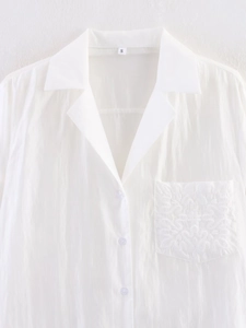 Detailed view of white shirt collar and chest pocket with intricate embroidery
