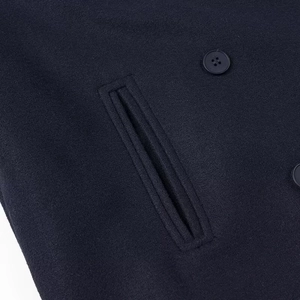 Vue détaillée du tissu en laine bleu marine avec poche passepoilée et bouton de veste