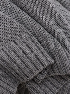 Gros plan d'un tricot gris foncé montrant la finesse des mailles et la texture côtelée