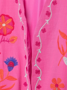 Gros plan de broderies florales colorées sur un gilet en coton rose fuchsia vif