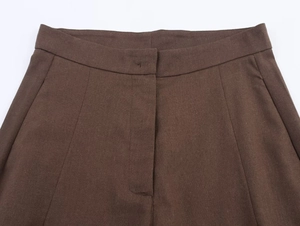 Detail of high-waisted brown trousers showing invisible closure and slanted side pockets