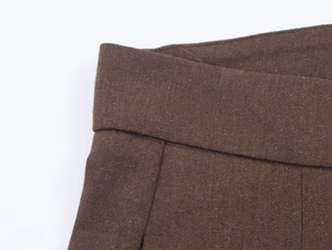 Detailed macro view of brown textured linen trousers with premium stitching and waistband