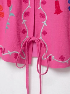 Détail de la broderie florale sur veste en coton-lin rose foncé avec lien à la base