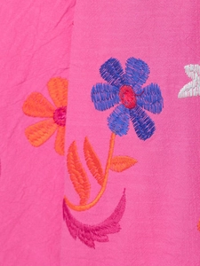 Détail de broderies florales bleues et oranges sur tissu rose en coton et lin