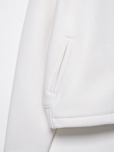 Detailansicht der weichen Fleece-Textur und Seitentasche der elfenbeinfarbenen Jacke