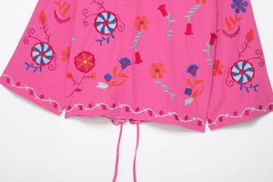 Gros plan sur les broderies roses et le cordon à la base d'une veste à manches longues