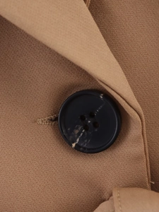 Close-up of brown fabric texture with a classic black four-hole button on the jacket
