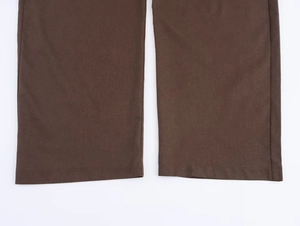 Detailed close-up of dark brown trousers hem with neat stitching and high-quality woven fabric