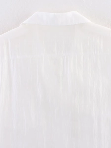Detailed view of white pleated shirt featuring back yoke and vertical textured fabric design