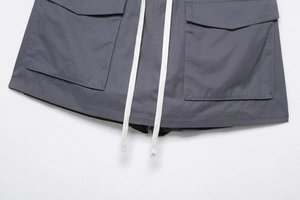 Detailed view of dark grey cargo shorts with large flap pockets and white cotton drawstrings