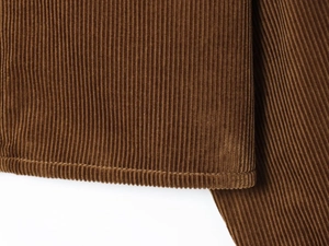 Detailed macro view of brown corduroy fabric texture and fine stitching on jacket hem