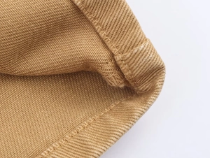 Detailed macro view of tan twill fabric texture and clean hem stitching of pants