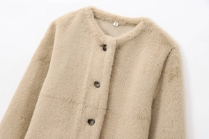Détail de la veste en fausse fourrure camel avec boutons marbrés et étiquette de taille