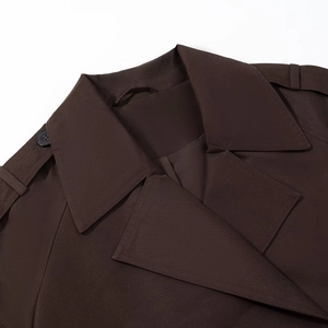 Detail of coffee brown short trench coat showing lapels, shoulder straps, and matte buttons