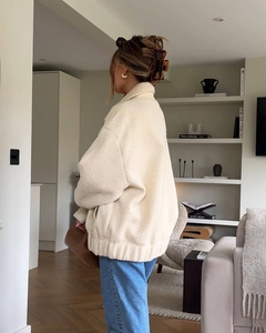 Detailed view of cream faux shearling jacket with ribbed hem and drop shoulder design