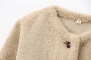 Détail de la texture en fausse fourrure beige d'une veste courte avec bouton et taille S