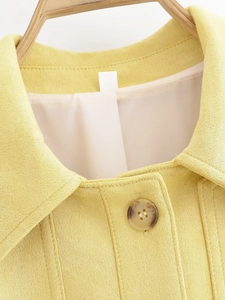 Close-up of lemon yellow suede jacket with lapel collar and marble pattern button
