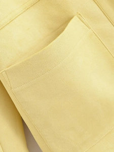 Macro shot of faux suede texture and precise stitching on a yellow jacket pocket
