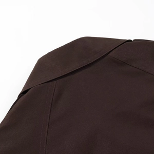 Close-up of double-stitched shoulder seams and collar on brown short trench coat jacket