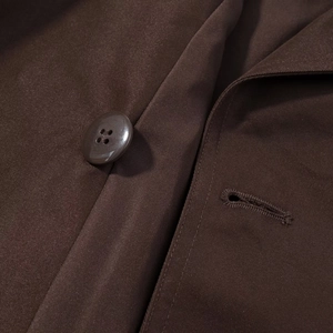 Macro detail of twill fabric texture and brown resin button on short trench coat