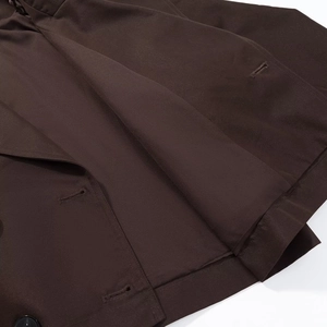 Close-up of chocolate brown twill fabric showing detailed stitching and lapel texture