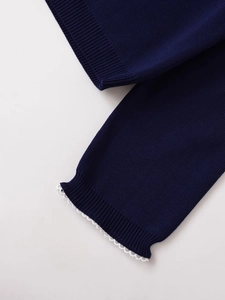 Detail of navy knit sleeves with white wavy lace cuffs and ribbed texture finish