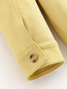 Detailed macro view of yellow suede jacket cuff featuring a premium amber resin button