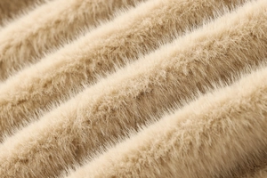 Gros plan sur la veste en fausse fourrure camel montrant la texture ondulée et douce