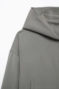 Detail view of grey hooded jacket with reinforced stitching and twill fabric texture
