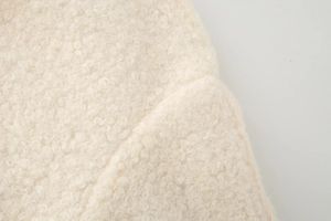 Close-up of beige fleece fabric texture showing curly wool details on a winter coat