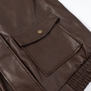 Close-up of brown PU leather jacket with snap pocket and ribbed elastic hem detail