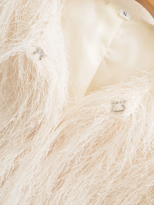 Detailed close-up of white feather jacket texture with silver metal hook closure