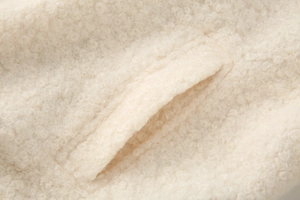 Detail of cream sherpa wool texture and diagonal side pocket on loose jacket