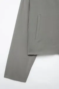 Detail of grey twill jacket showing precise stitching and functional side pocket