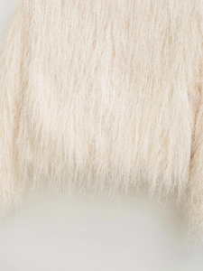 Close-up of cream white shaggy faux fur texture on a long-sleeved cropped jacket