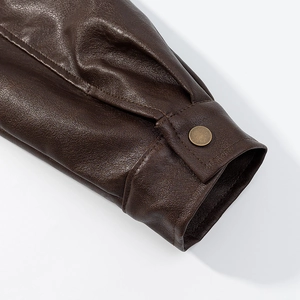 Detailed macro view of the sleeve cuff on a brown leather jacket with vintage metal button