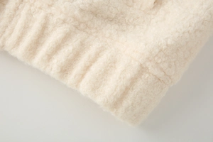 Detail of beige faux wool fabric texture with high-quality knitted ribbed cuff finish